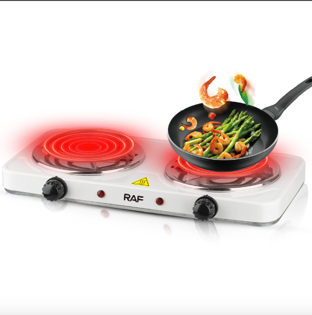 Portable stove with a frying pan containing shrimp and asparagus on a white background