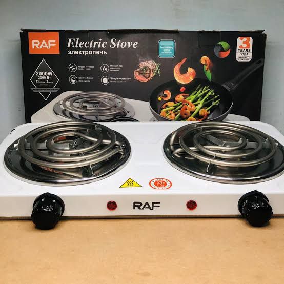 RAF electric stove with a pan of food on a wooden surface, next to its packaging.