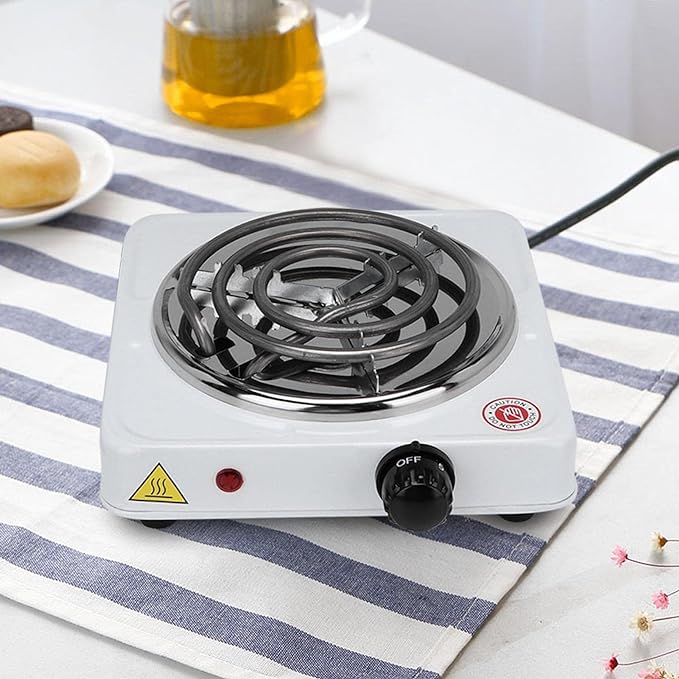 Single burner electric stove on a striped tablecloth with a small plate of buns in the background.