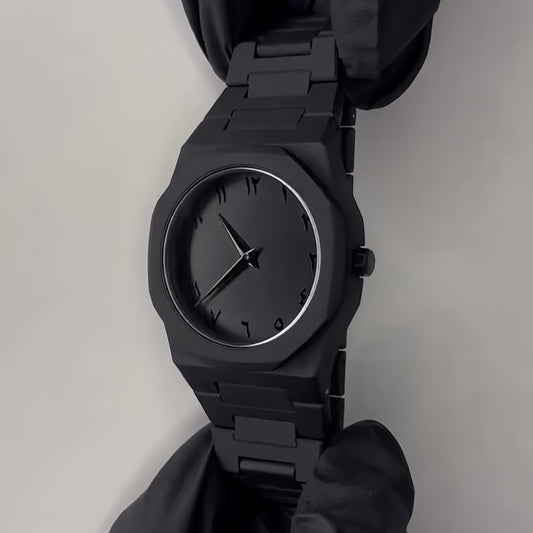 Black watch held by a gloved hand on a light gray background