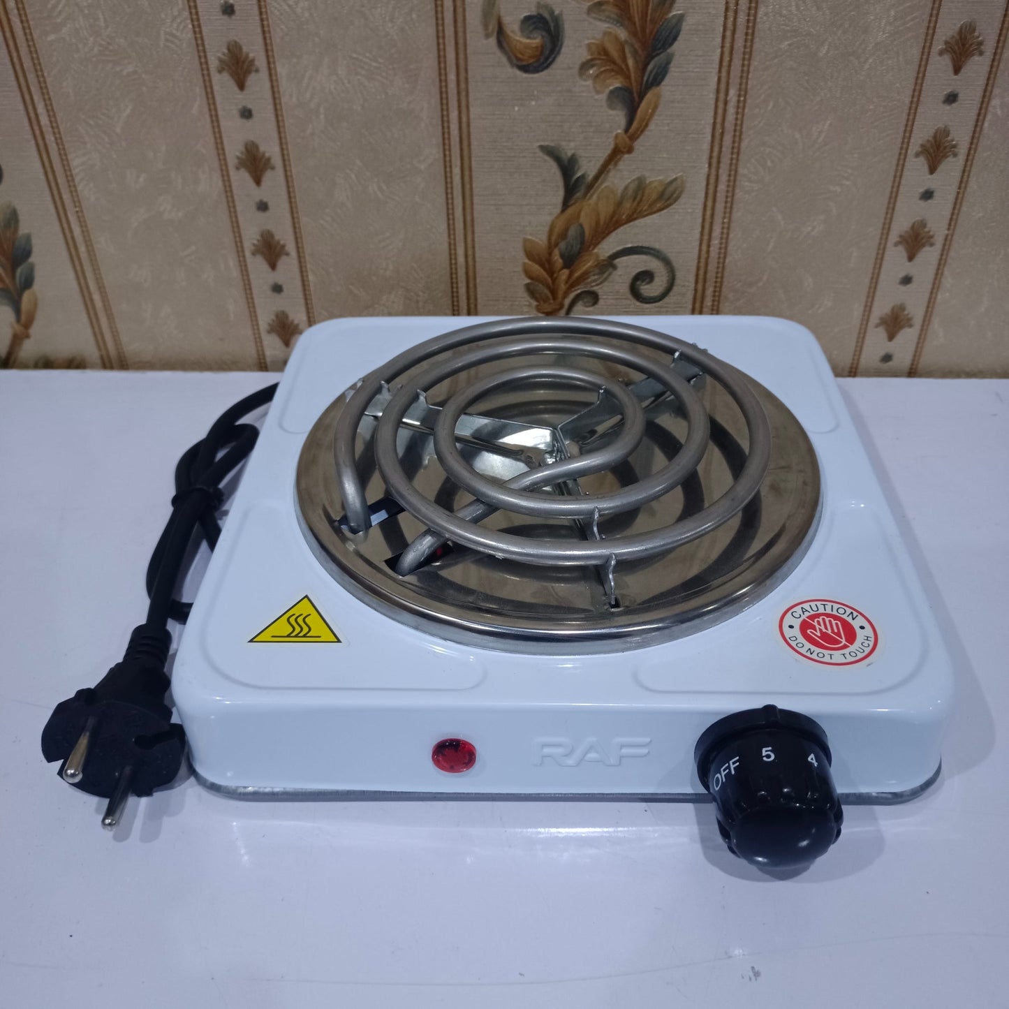 Single burner hot plate with control knob on a white surface