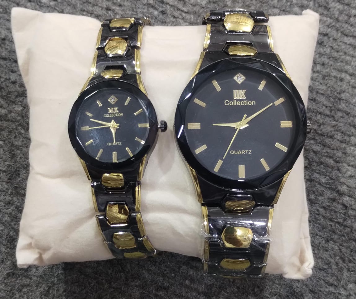 Two black and gold wristwatches on a white cushion with a gray background