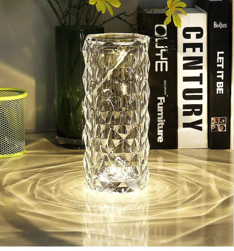 Crystal glass lamp on a reflective surface with books and decorative items in the background