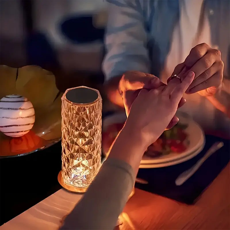 Person holding a hand with a ring next to a textured lamp on a table.