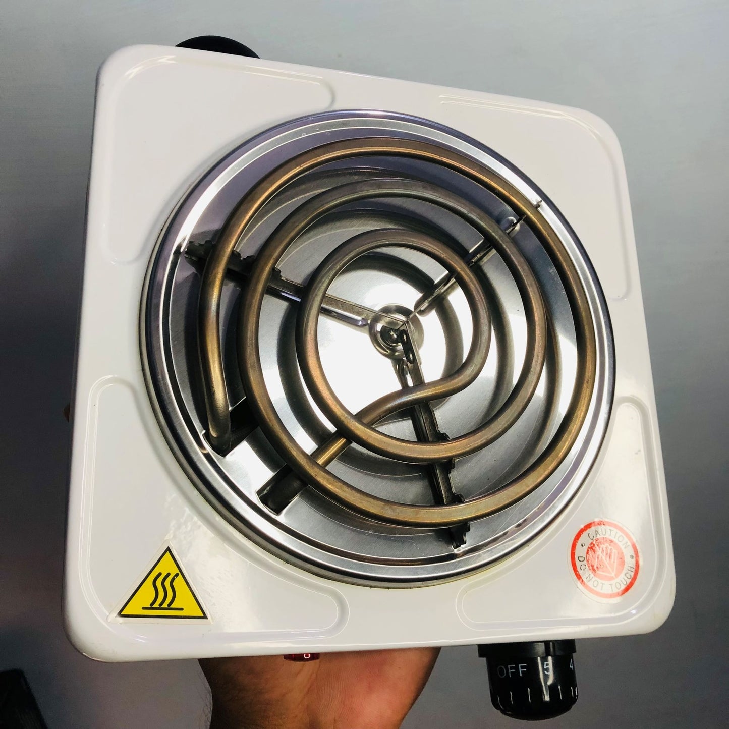 Single burner electric stove with spiral heating element on a gray background